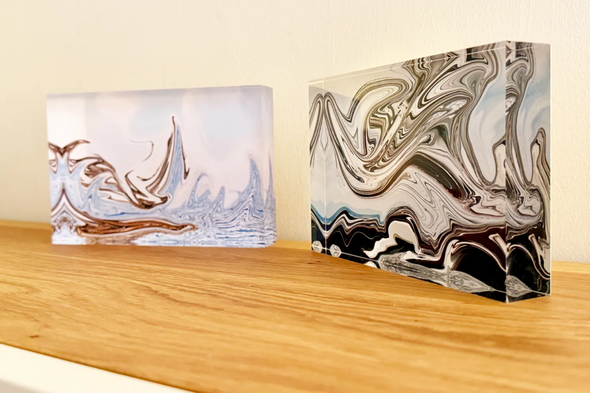 zwei künstlerisch gestaltete Wellen als Foto im Acrylglasblock stehen auf einer Holzoberfläche