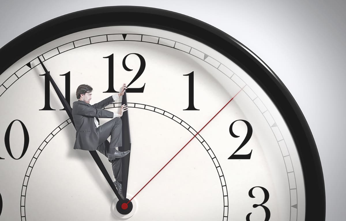 Zeitmanagement: Mann in Uhr versucht die Zeiger anzuhalten - Zeitmanagement - netzwerk managementberatung | coaching